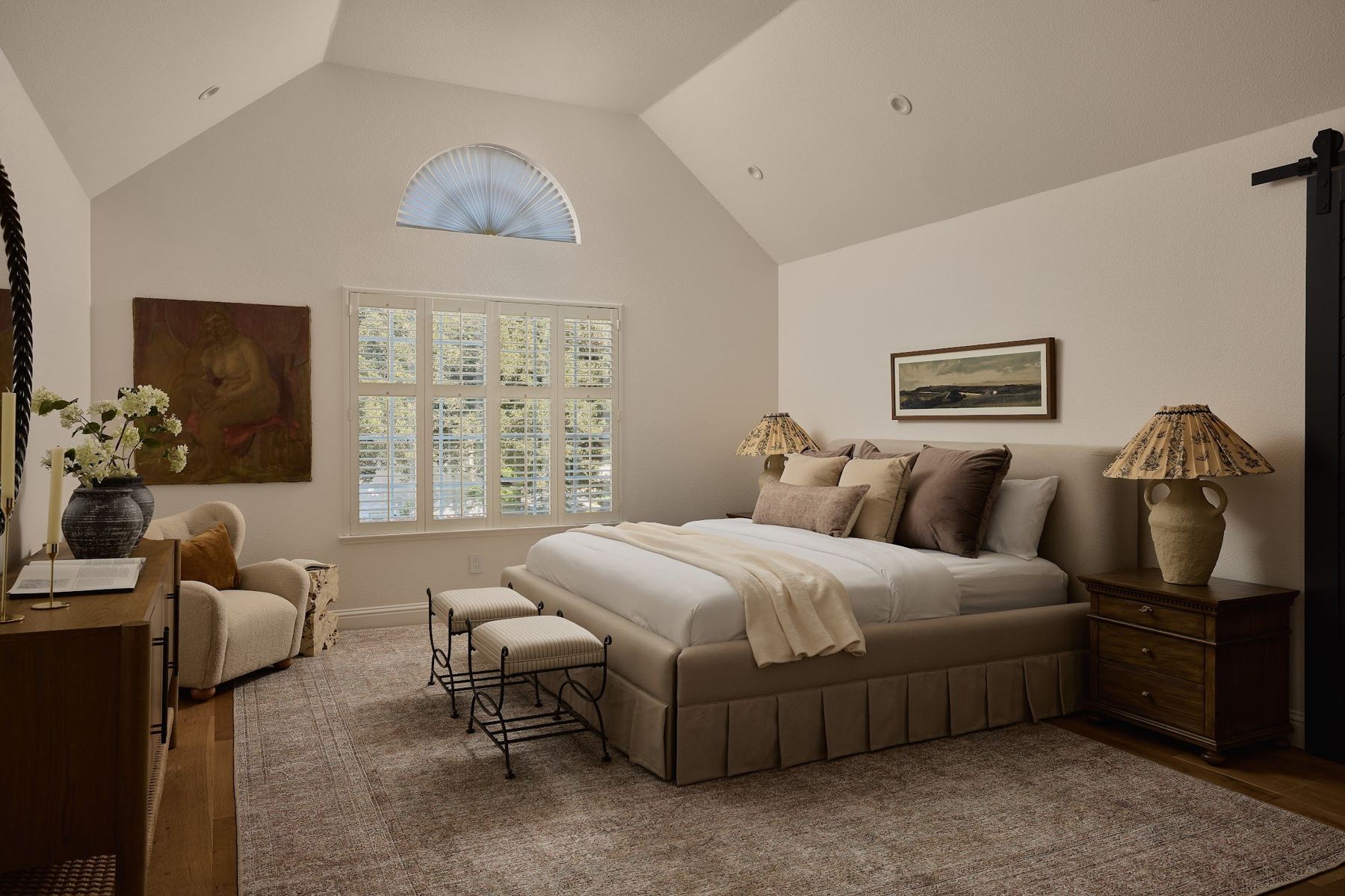 Primary bedroom with vaulted ceiling and arched window